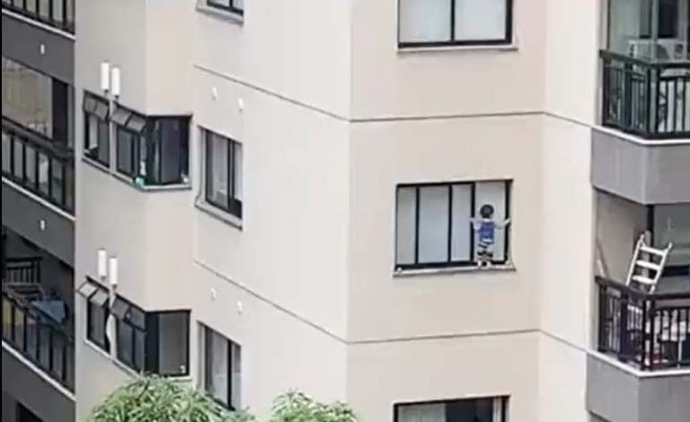 Criança pendurada prédio