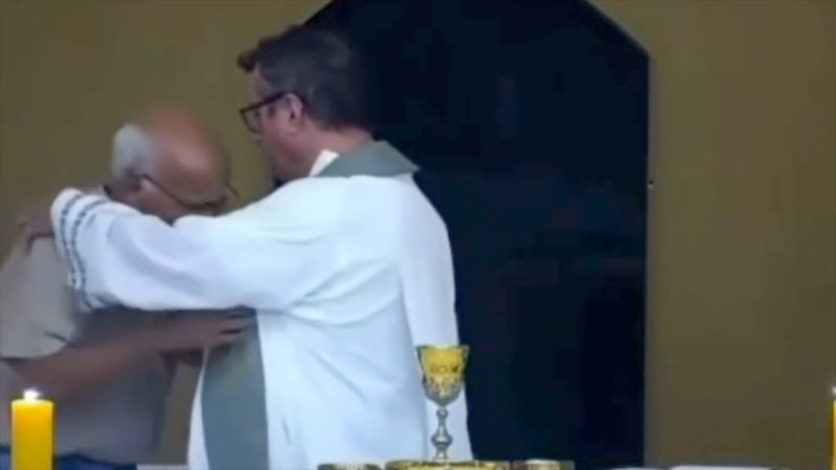 Idoso abraçando padre durante missa, emocionado, em Tubarão.