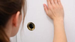 Mão de mulher encostada em porta de banheiro sem maçaneta, em imagem ilustrativa