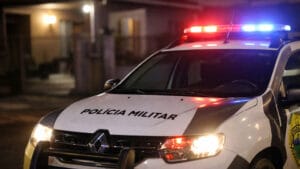 Viatura da Polícia Militar do Paraná com giroflex ligado em frente a residência