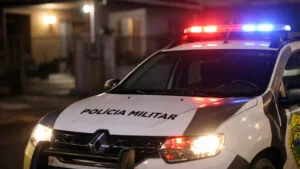 Viatura da Polícia Militar do Paraná com giroflex ligado em frente a residência