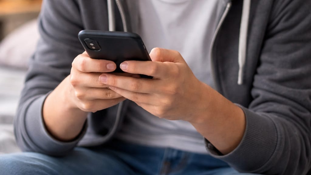 Imagem ilustrativa mostra mão de adolescente manipulando celular