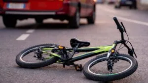 Bicicleta caída no asfalto com ambulância do Corpo de Bombeiros desfocada ao fundo