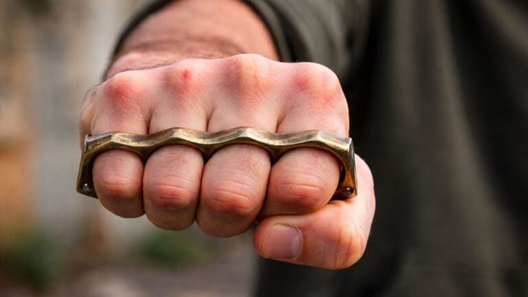 Imagem ilustrativa de mão segurando um soco inglês metálico