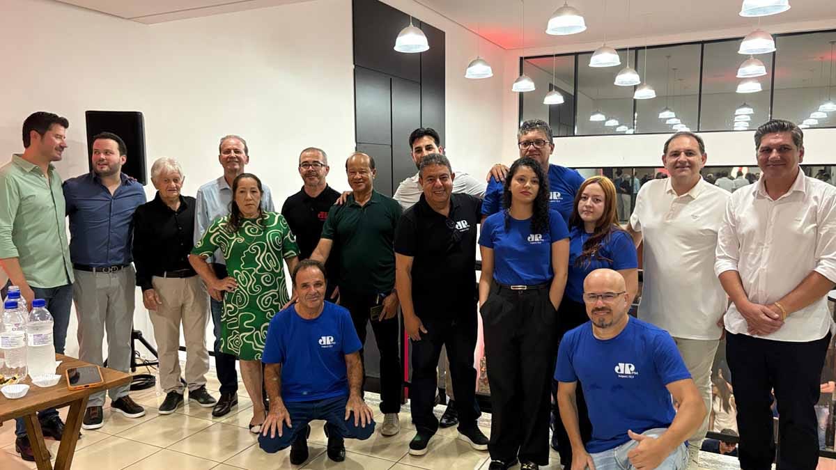 Proprietários e equipe da Jovem Pan reunidos em estúdio durante evento, posando para foto coletiva.