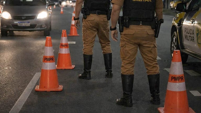 Policiais militares realizam blitz noturna com cones em avenida urbana