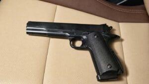 Pistola de airsoft sem ponteira laranja sobre banco de carro em tons creme e marrom
