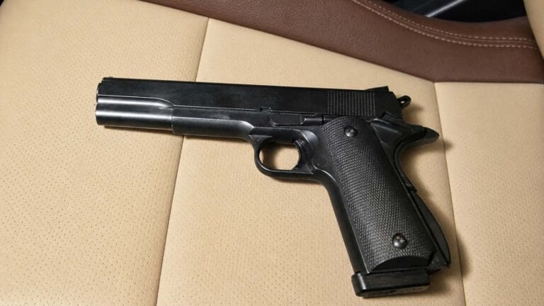 Pistola de airsoft sem ponteira laranja sobre banco de carro em tons creme e marrom