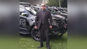 Sargento Rogério Knaipp de terno em frente a viaturas da Polícia Militar do Paraná