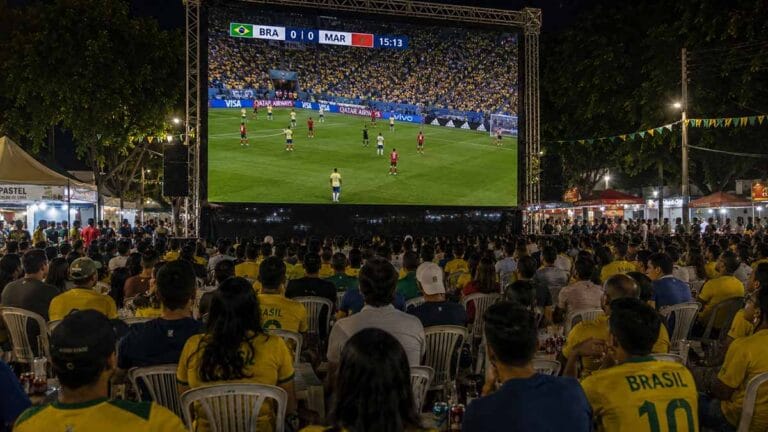 Torcedores acompanham partida da seleção brasileira em um telão durante evento noturno