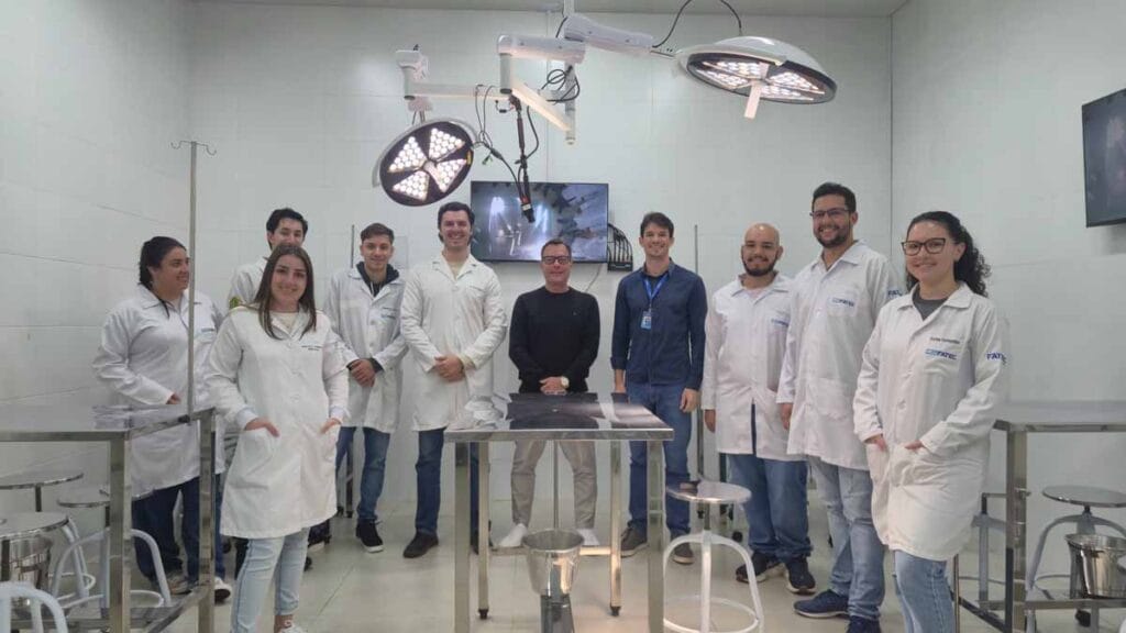 Professor demonstra procedimento em centro cirúrgico simulado da Fatec Ivaiporã enquanto alunos acompanham as imagens em monitores.