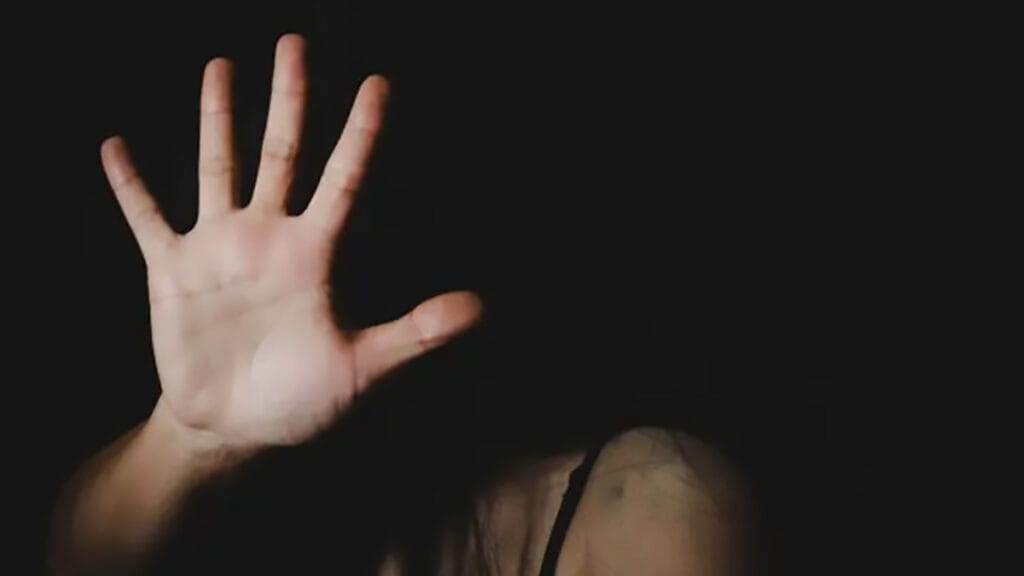 Mulher se protege com a mão em imagem sobre violência doméstica