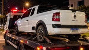 Saveiro branca sendo transportada por um guincho durante a noite.